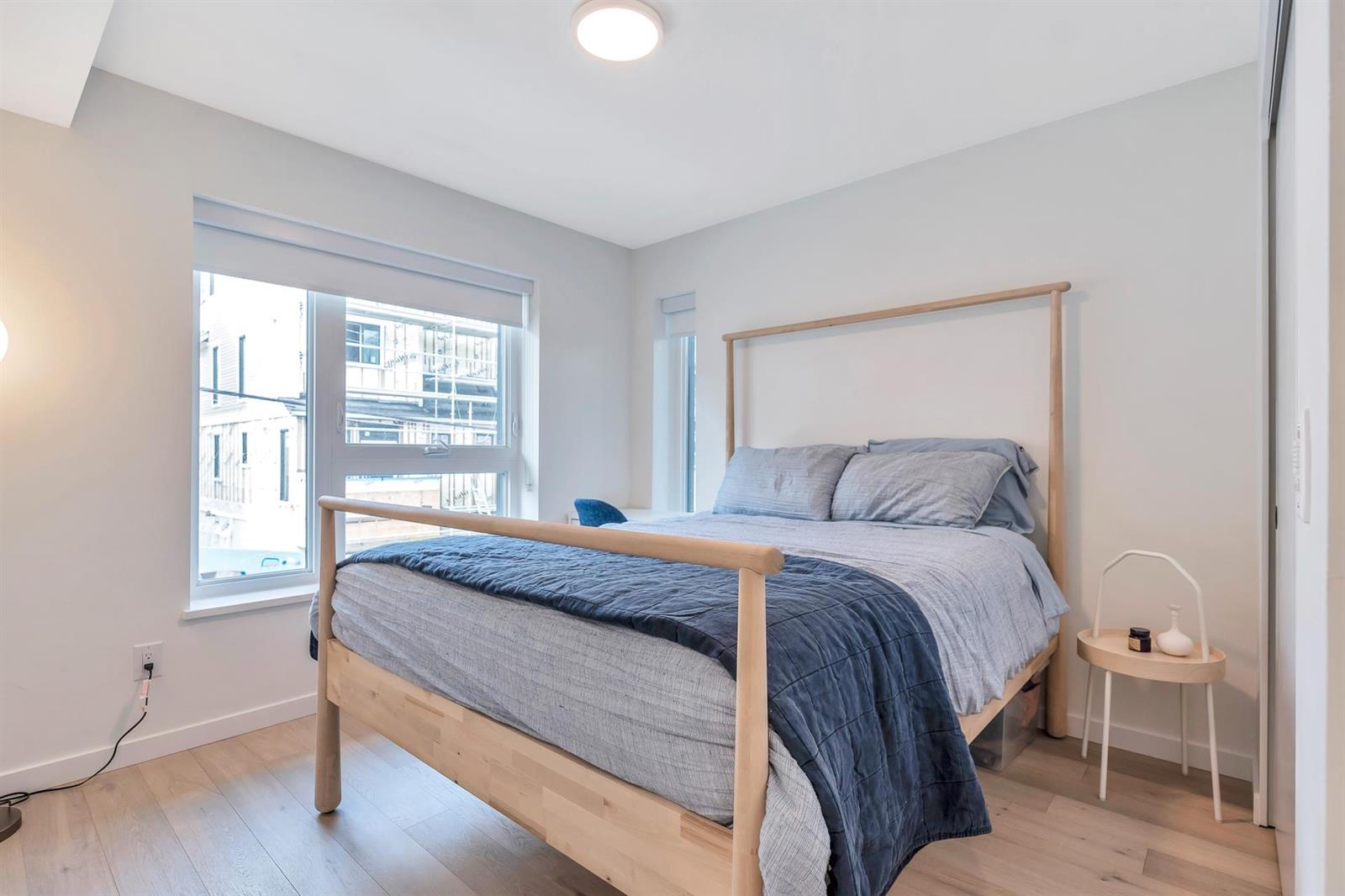 A bedroom with a timber bedstead and a window looking out over the street.