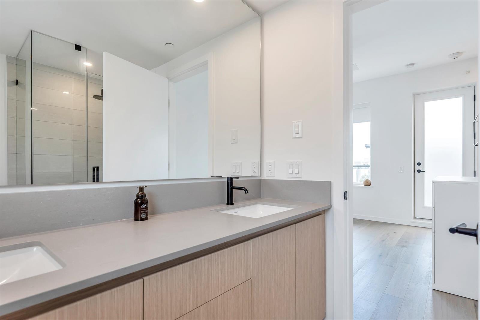 The ensuite, a long vanity beneath twin mirrors with the shower glazed at the end.