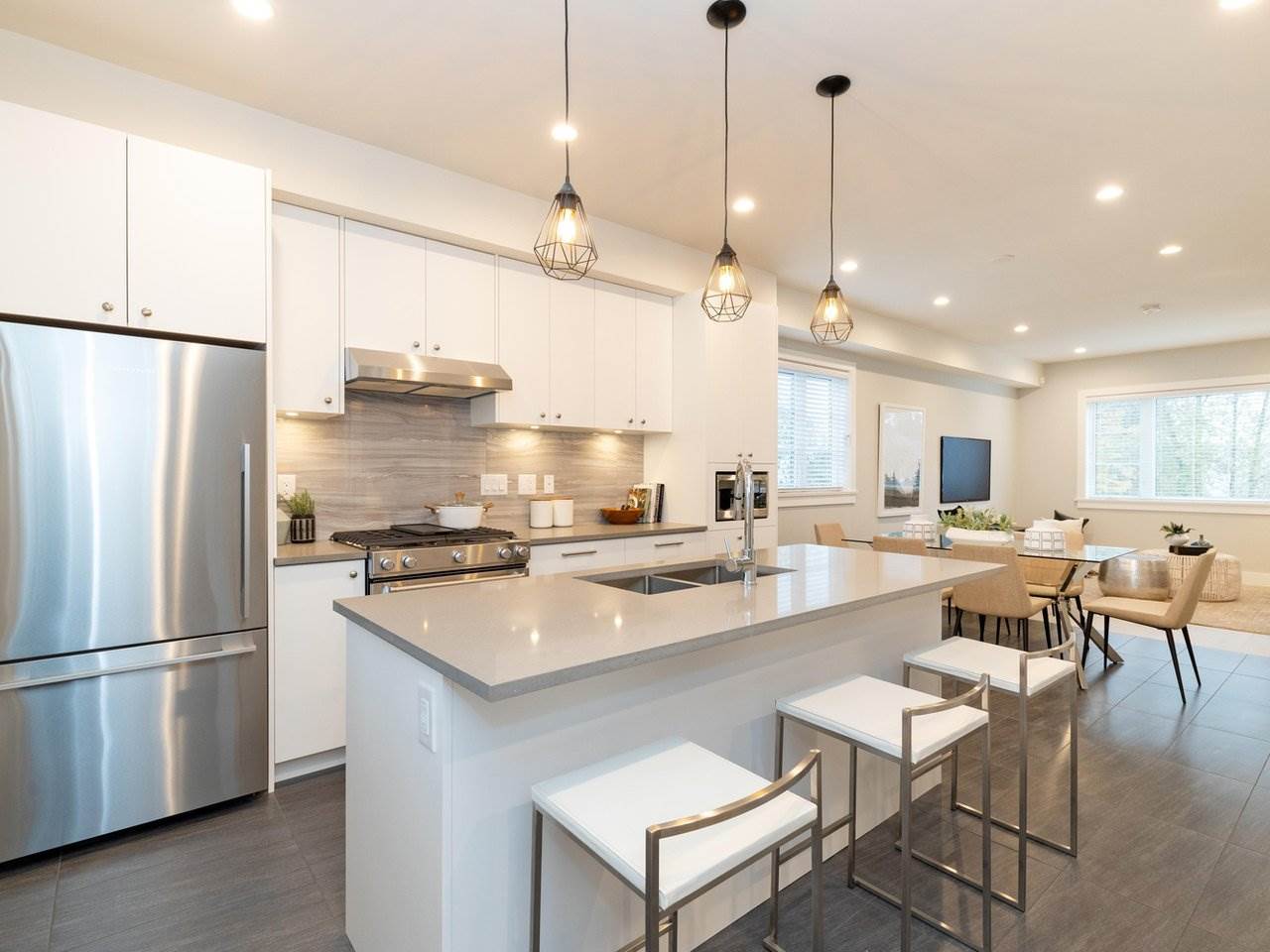 The kitchen island from the far side, pendant lights above it and the dining and living rooms running away behind.