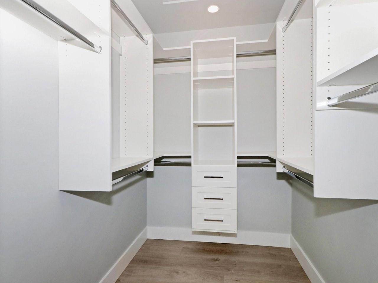 The walk-in closet, hanging rails on three sides with drawers built in.