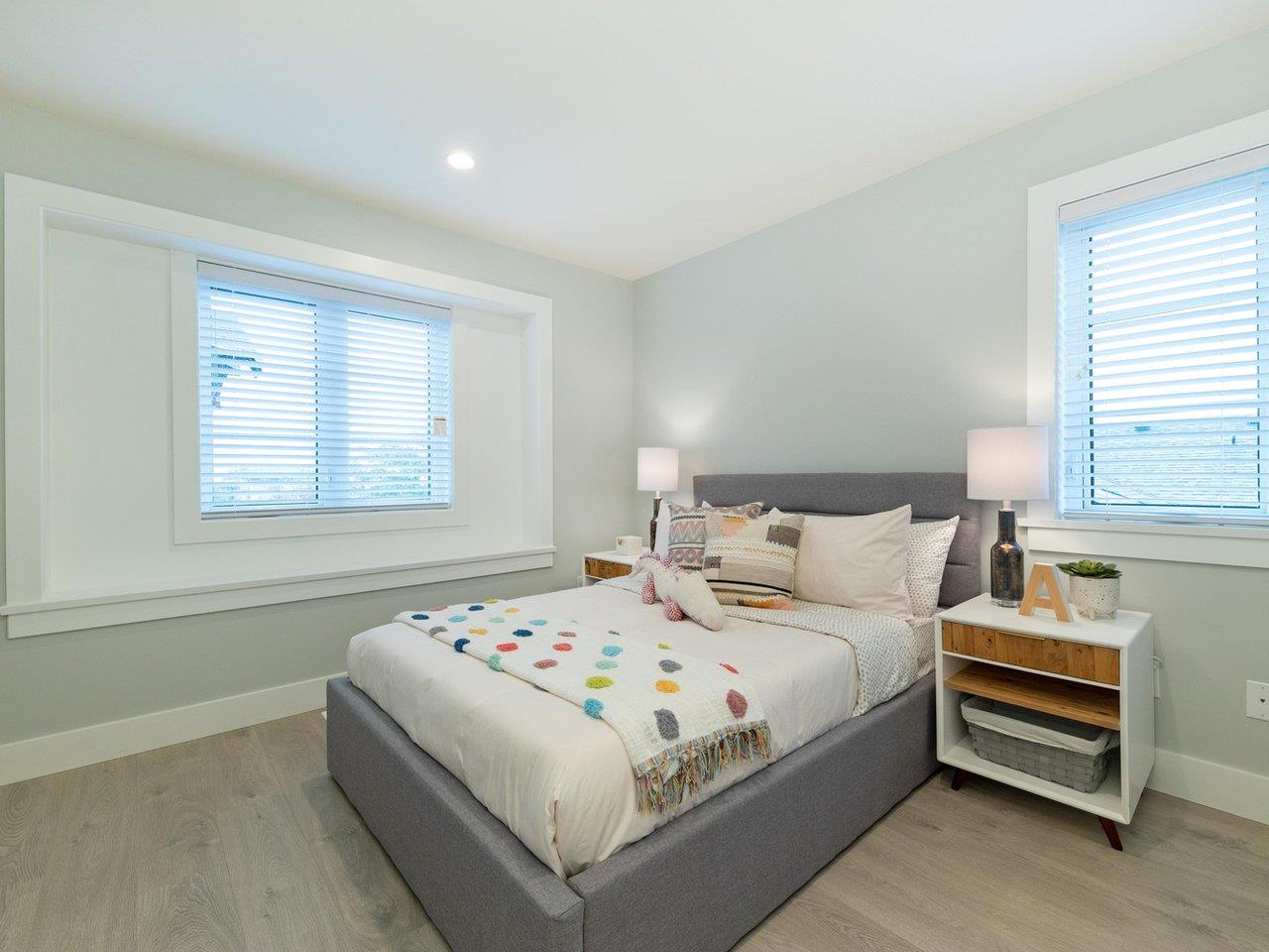The third bedroom, a bed between windows on two walls.