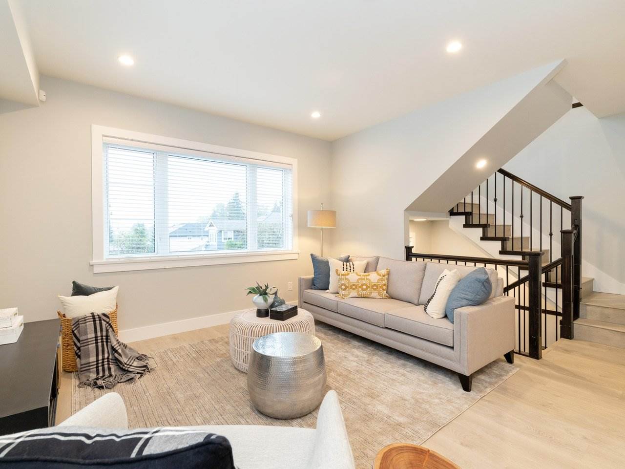 The living room, a sofa under the windows with the staircase rising behind it.