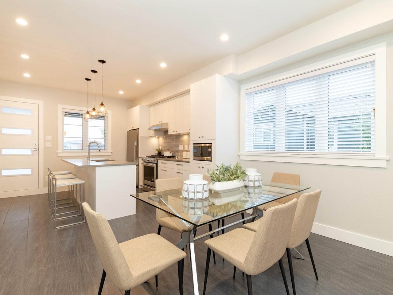 The dining table and chairs with the kitchen counter behind.