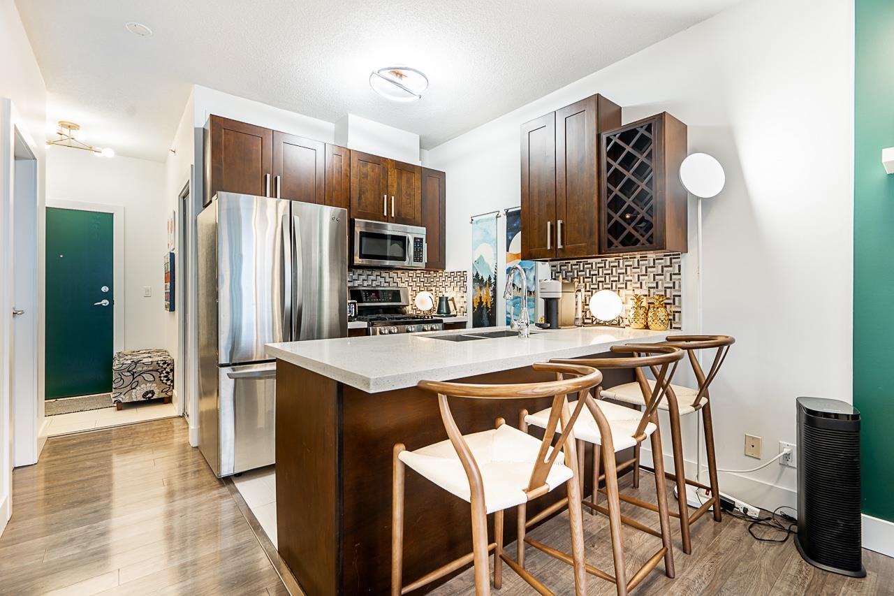 The kitchen from the entry, the island and breakfast stools with the tall cabinetry behind.