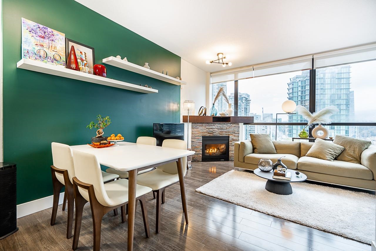 The dining table set for four beneath a pendant, the living room and the fireplace behind it.