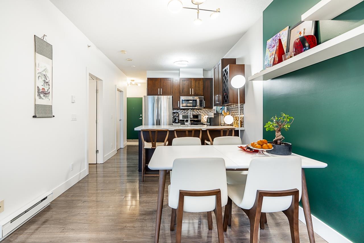 The dining table from the hallway, the kitchen along the right and the green wall at the far end.