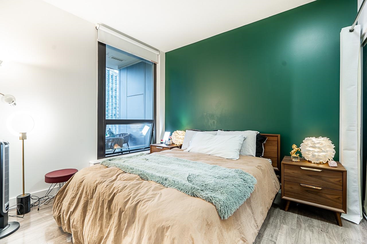 The bedroom, the bed against a deep green wall with a window on the left looking out to the towers.