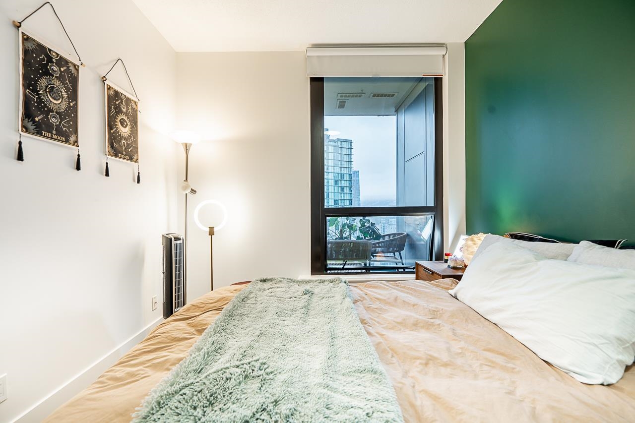 The bedroom from the doorway, the window and its city view at the far end of the room.