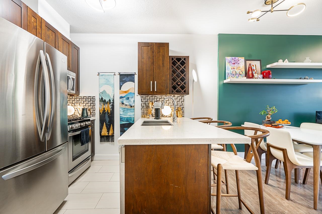 The kitchen from the far end, stainless refrigerator on the left and the island with its stools on the right.