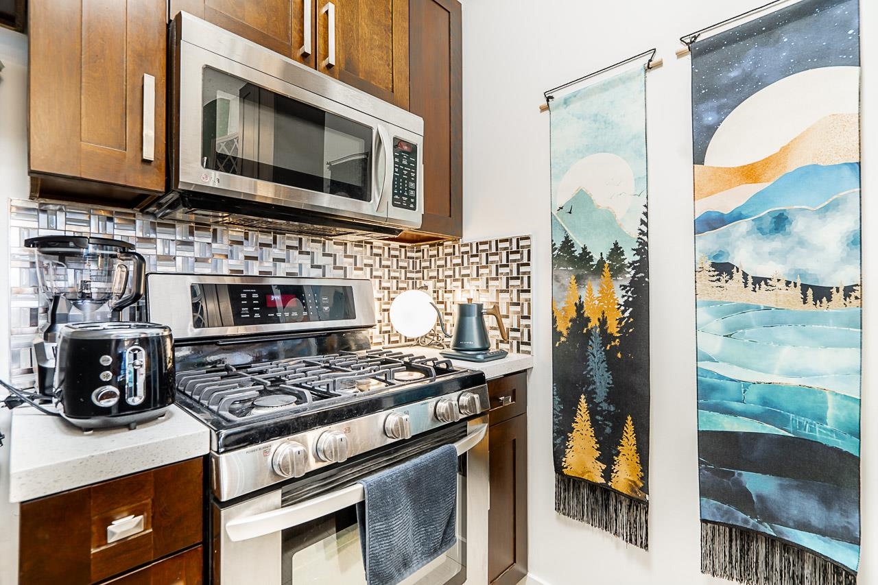 The kitchen work wall, gas range and stainless hood between patterned tile and the wine rack above.