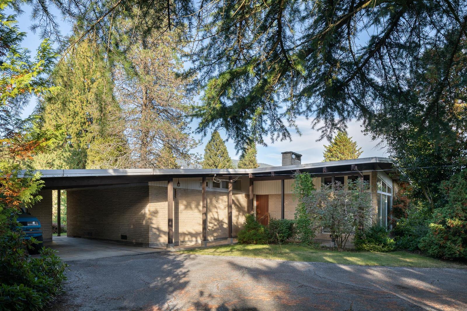 The front of the house from the driveway, a wide carport with the timber roof running out over it.
