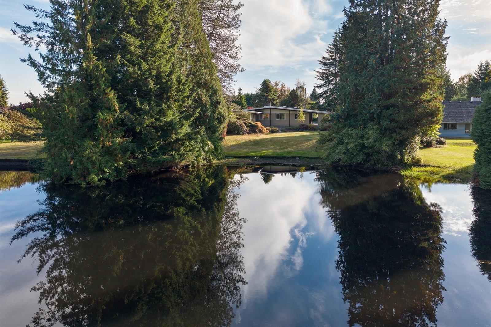 The water still enough to hold the reflection of the trees and the clouds.