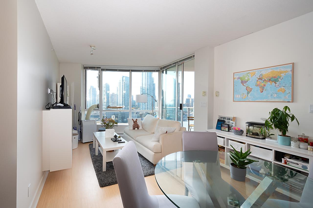 The living room from the window end, the seating on one side and the dining table with its glass top on the other.