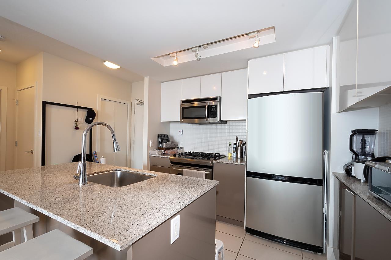 The kitchen island, a granite counter with the sink set into it and the stainless fridge behind.