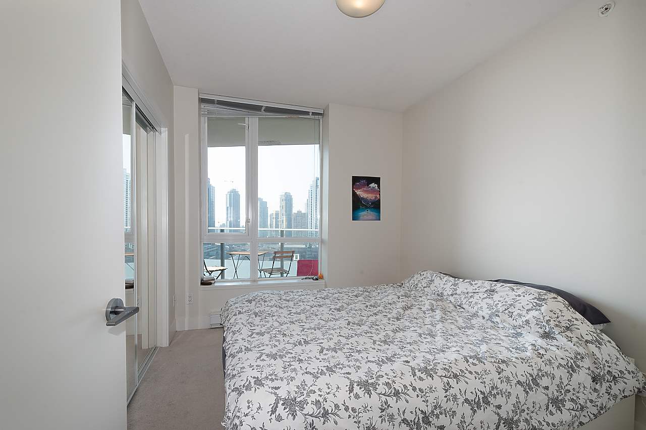 The bedroom, the bed beside a window that carries the same view west over the city.