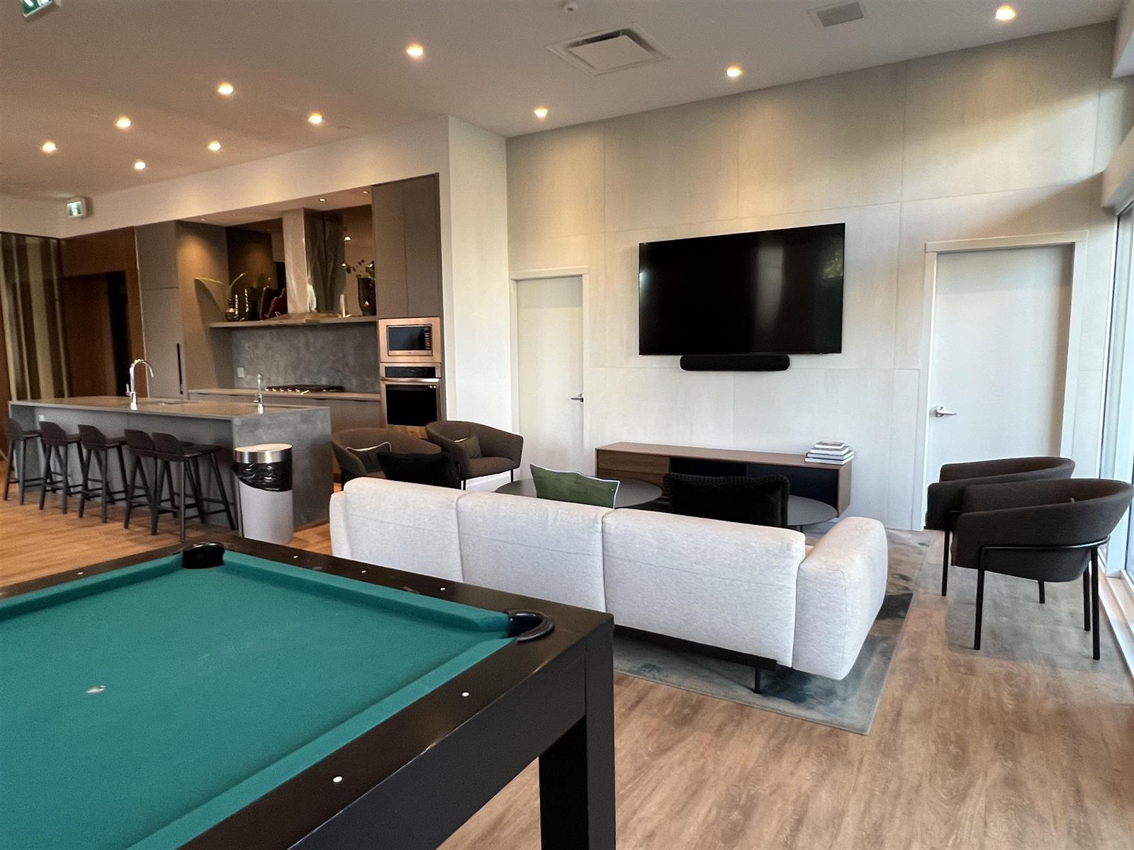 The games end of the lounge, a billiard table in front of a wall-mounted television.