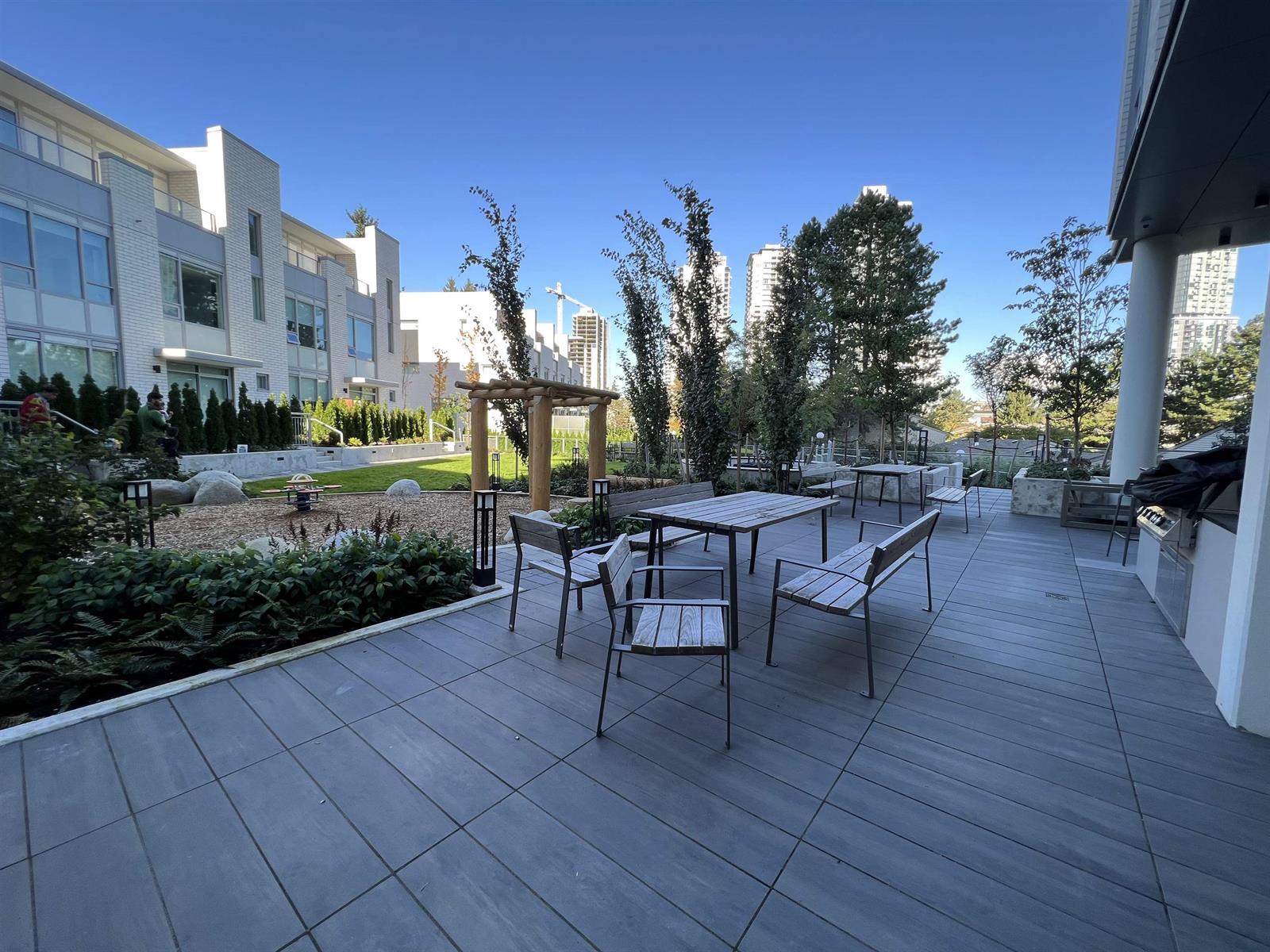 The outdoor terrace, tables and chairs under a pergola with planting around them.