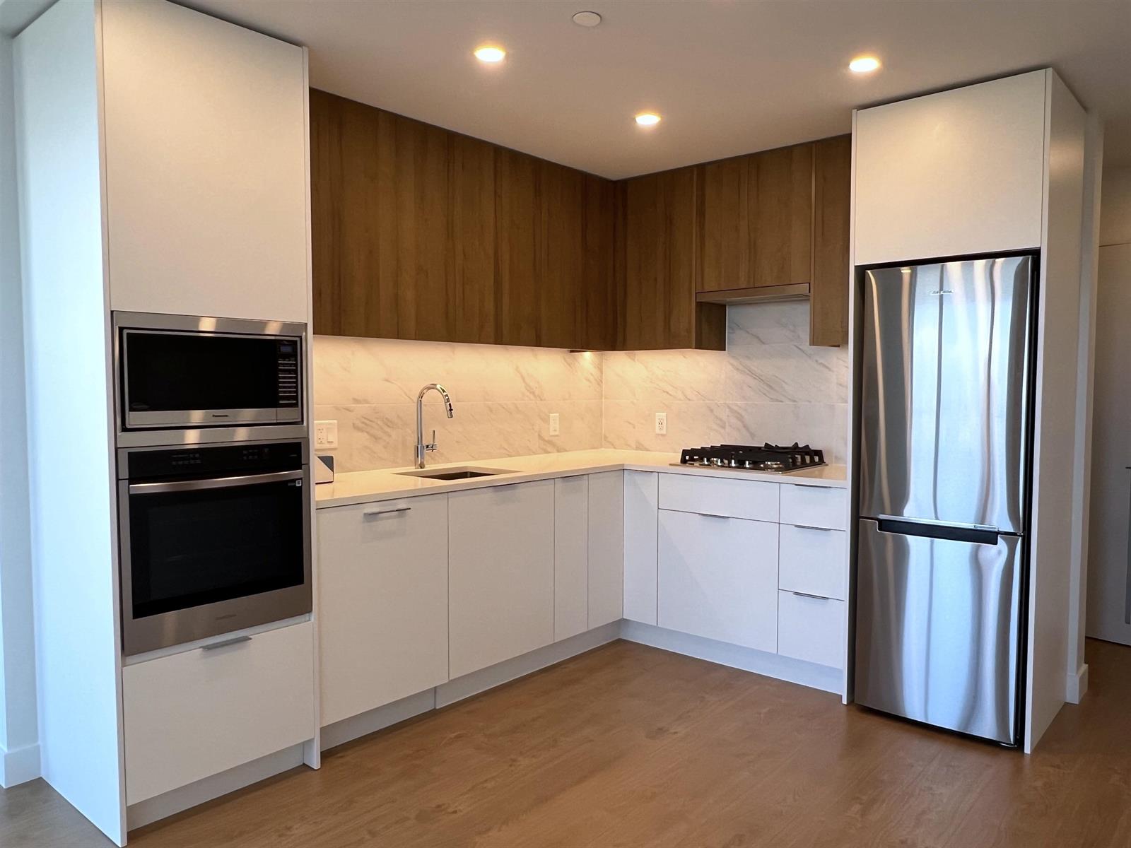 The kitchen: timber upper cabinets over white below, with a gas range, a built-in oven and a stainless refrigerator.