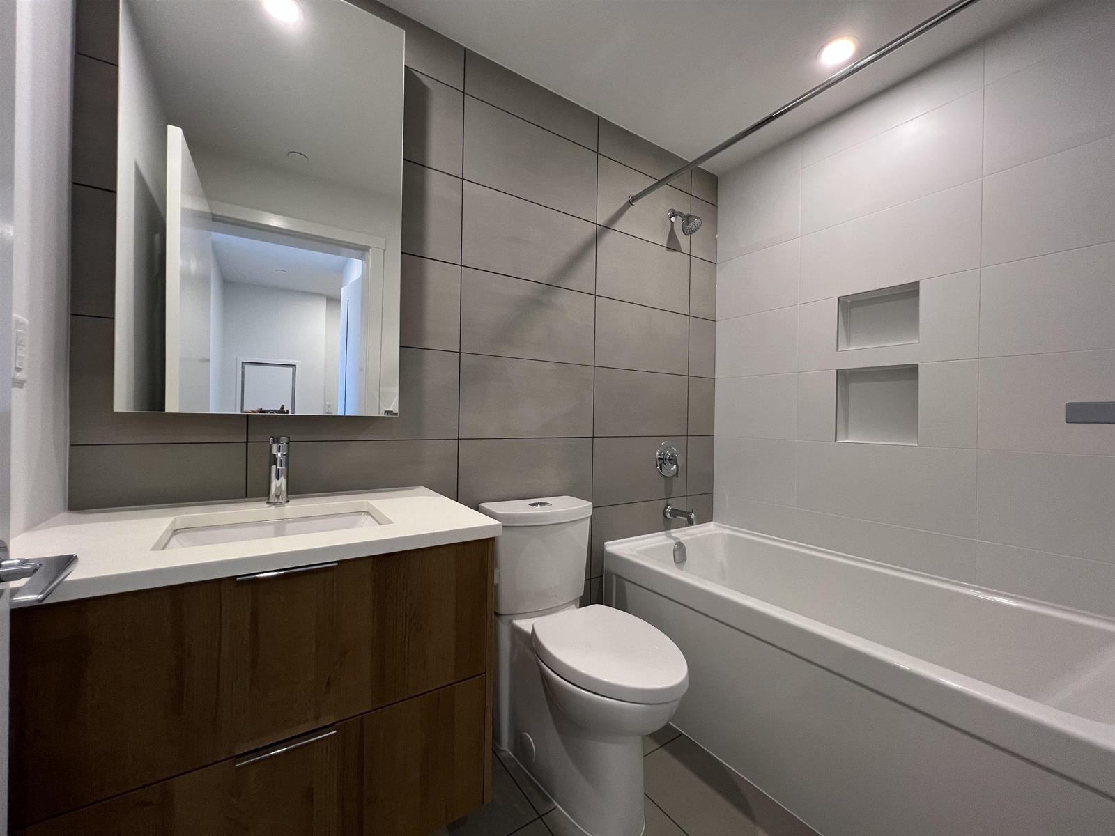 The second bathroom, a bath under tiled walls with a niche set into them.