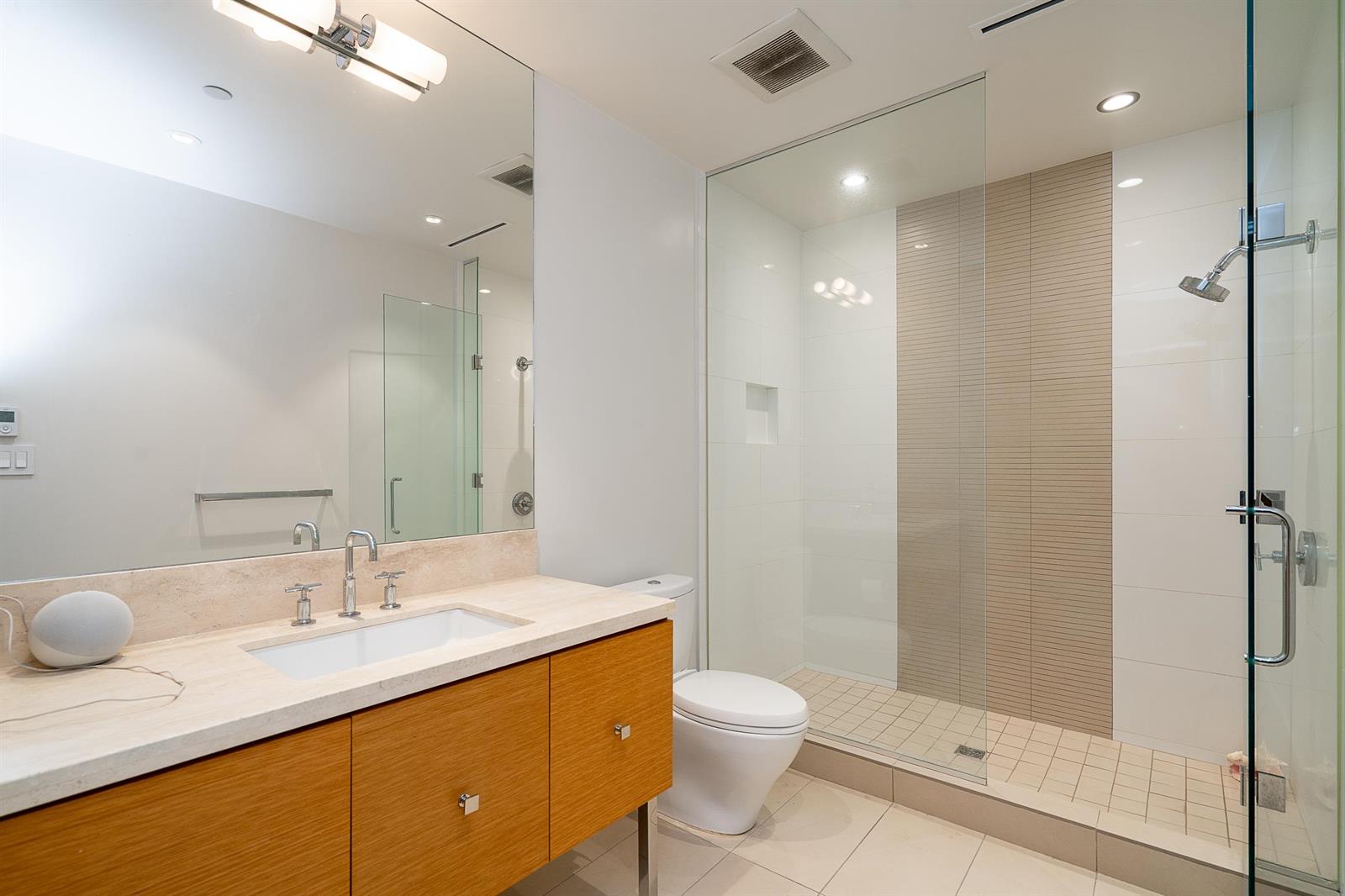 The second bathroom, a single vanity with a glass shower beside it.
