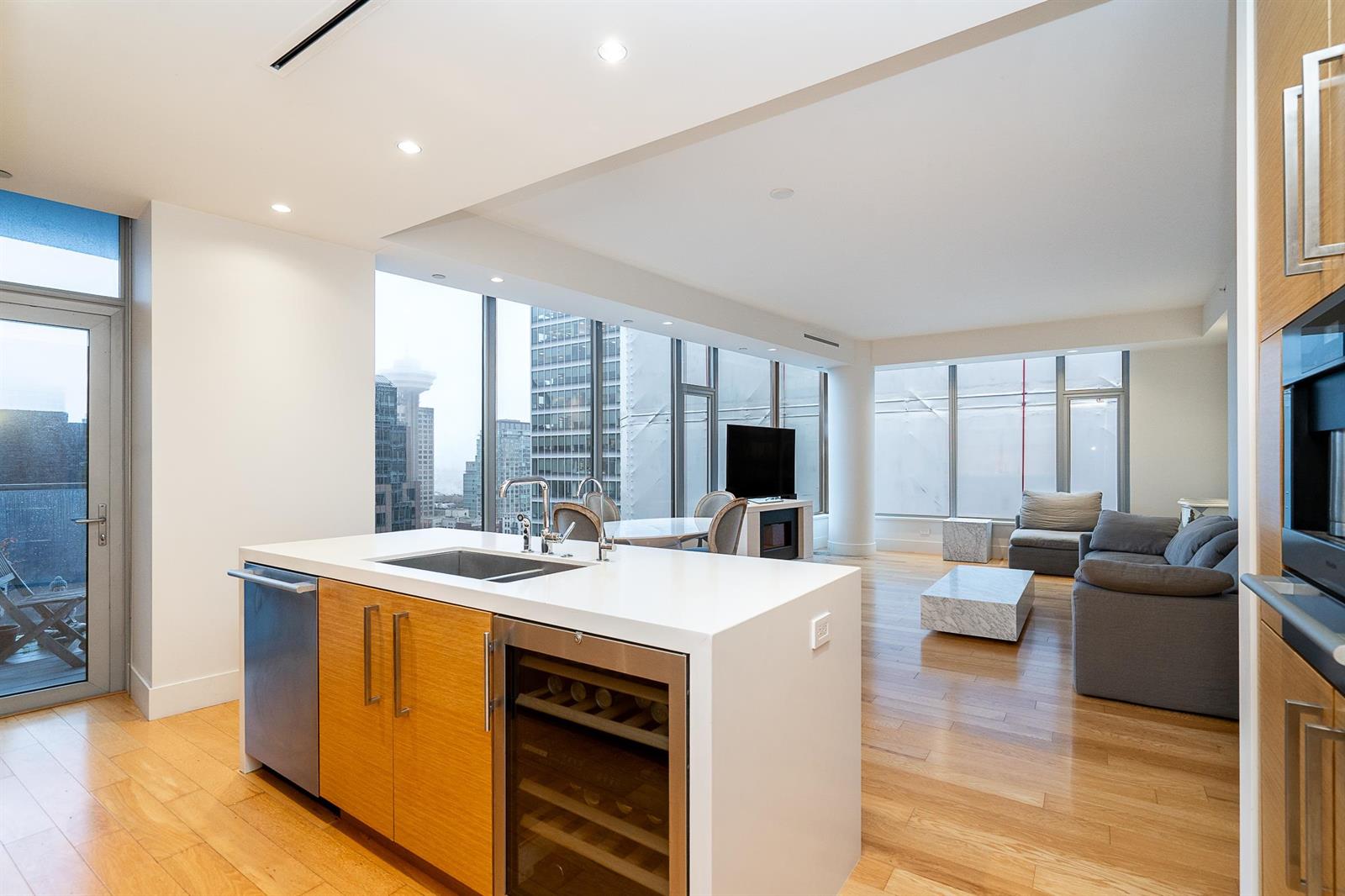The kitchen island seen from the living room, the wine fridge below the counter and the seating area beyond.