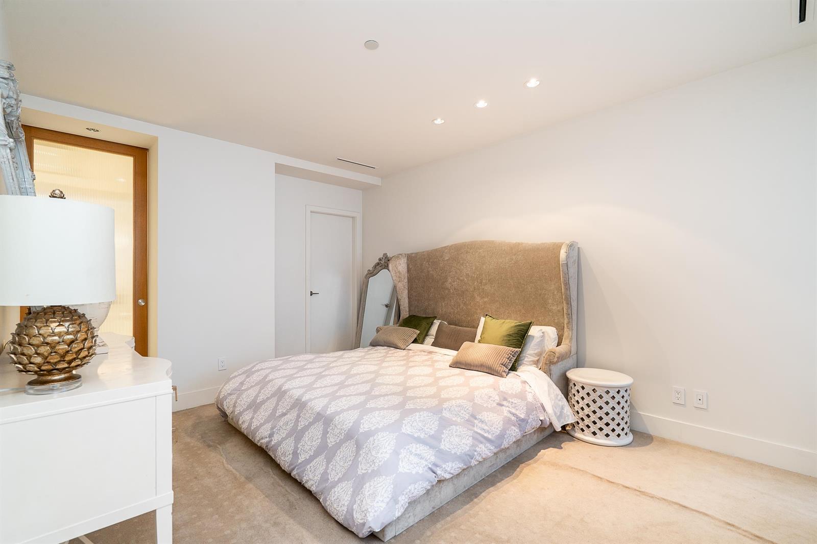 The primary bedroom, the bed against a panelled wall with a lamp and a window to the left.
