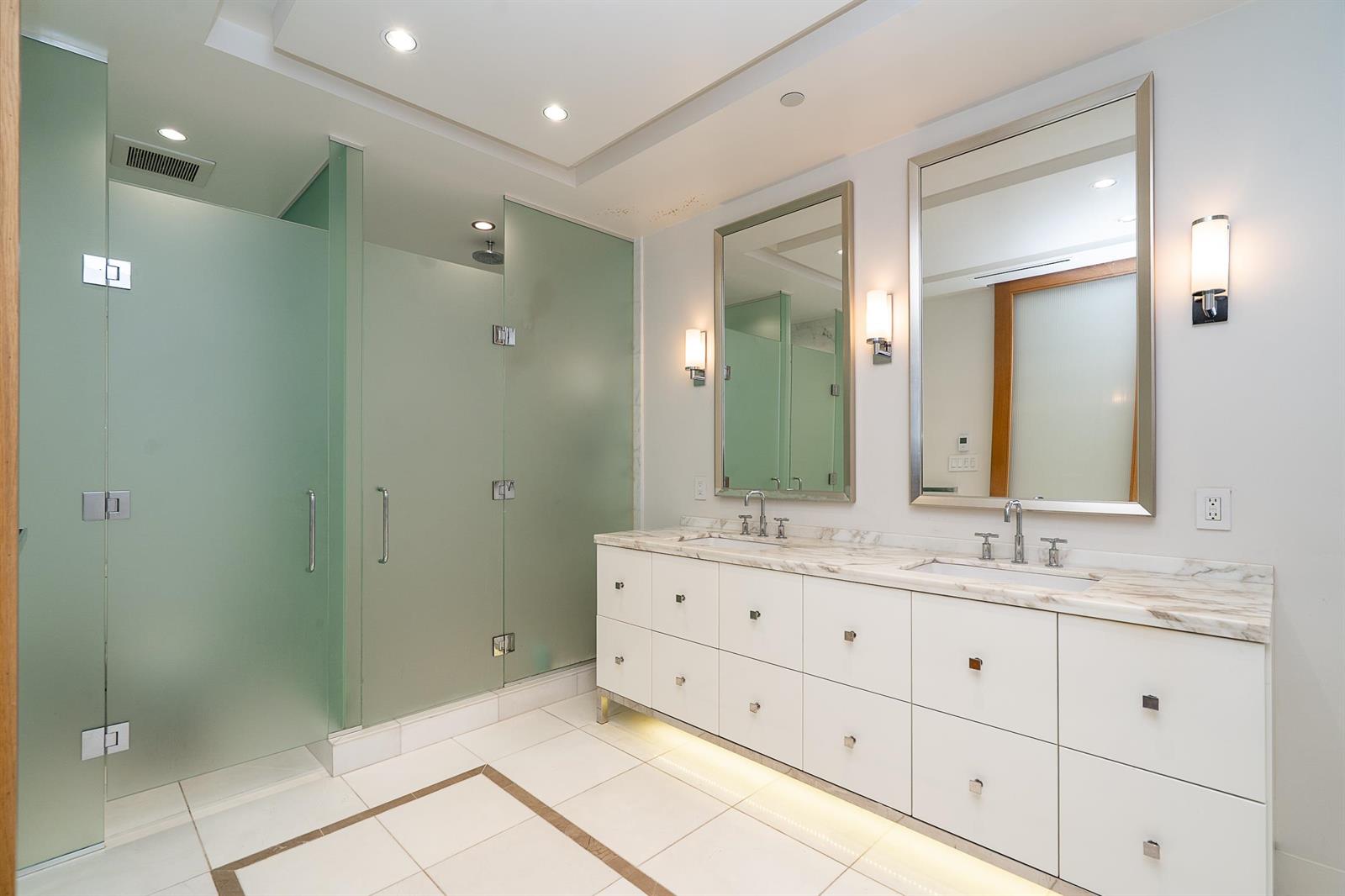 The ensuite, a double vanity in marble between a glass shower and a pair of mirrors.