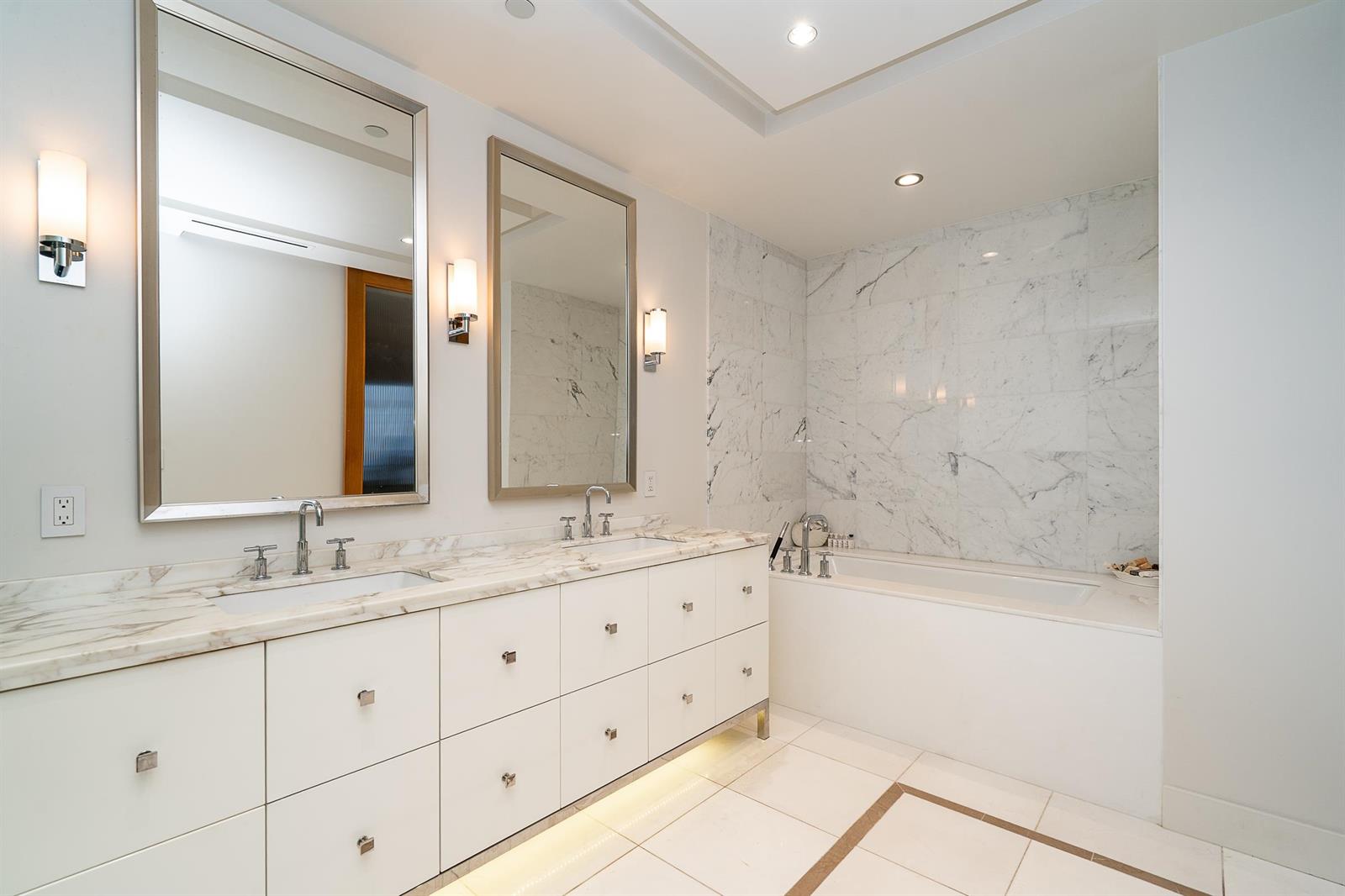 The ensuite from the other end, the double vanity on the left and a marble tub set into the wall.