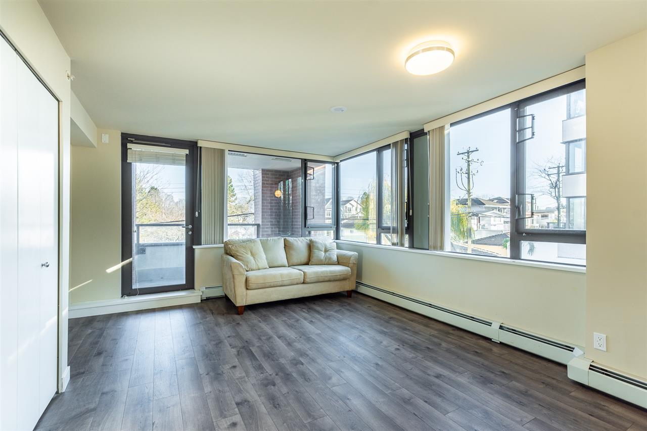 The living room in the corner of the building, windows along two walls and a sofa under them.