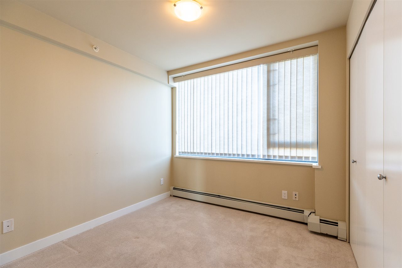 The second bedroom, blinds drawn across a tall window.