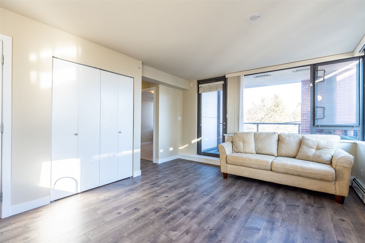 The living room from the far corner, the balcony door open at one end and closets along the wall.