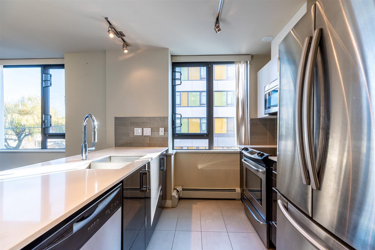The kitchen along its window wall, the range and the counter running out to the light.