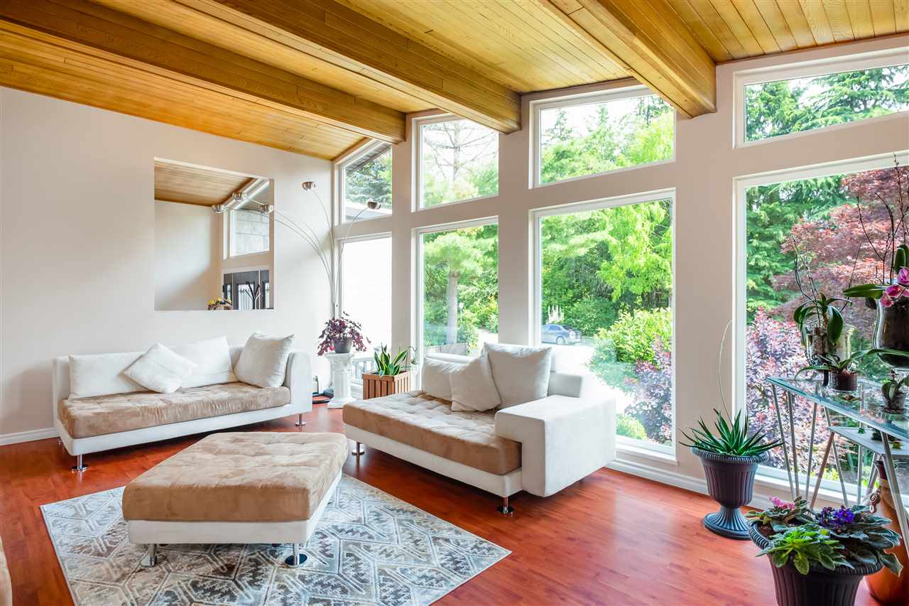 The living room under the vaulted cedar ceiling, a sofa along the window bench with the garden through the glass.