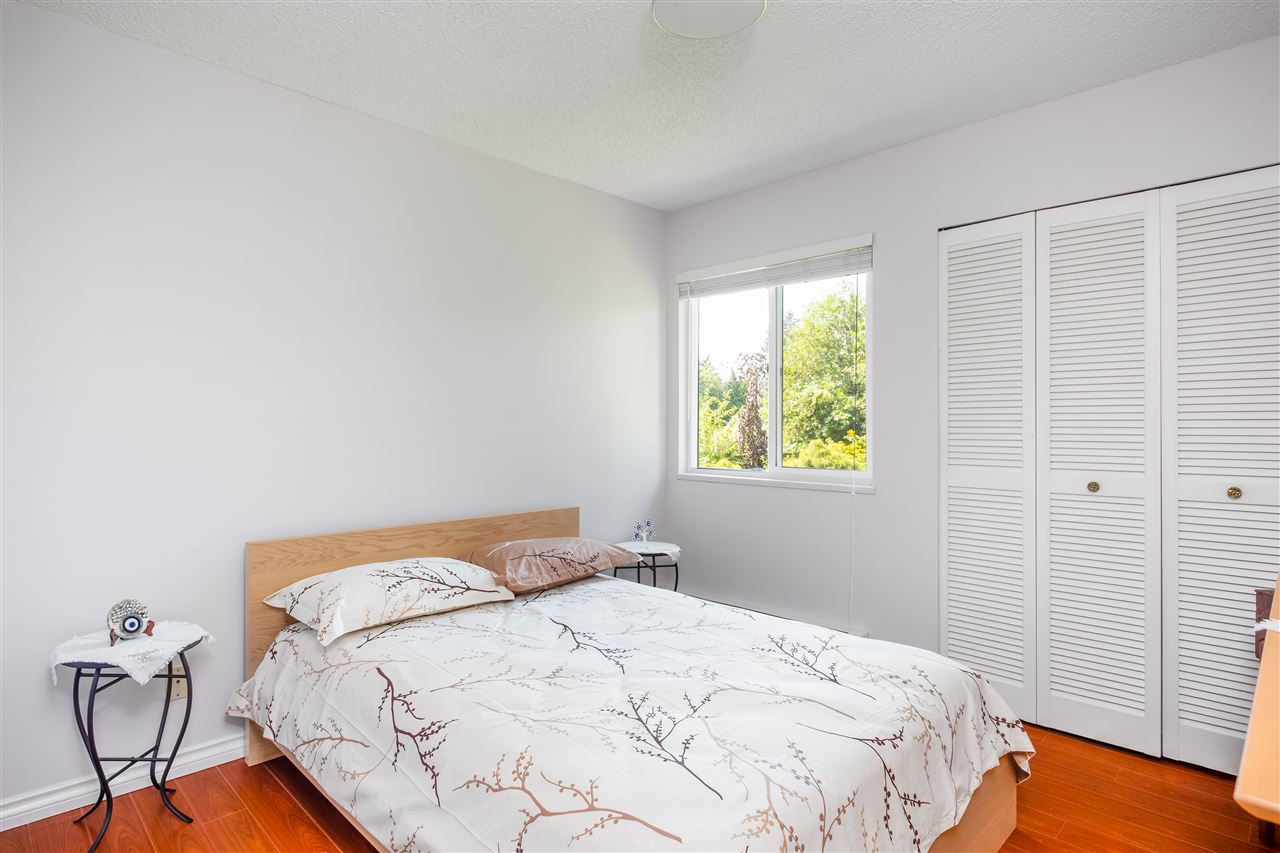A bedroom with louvred closet doors, the bed under the window.