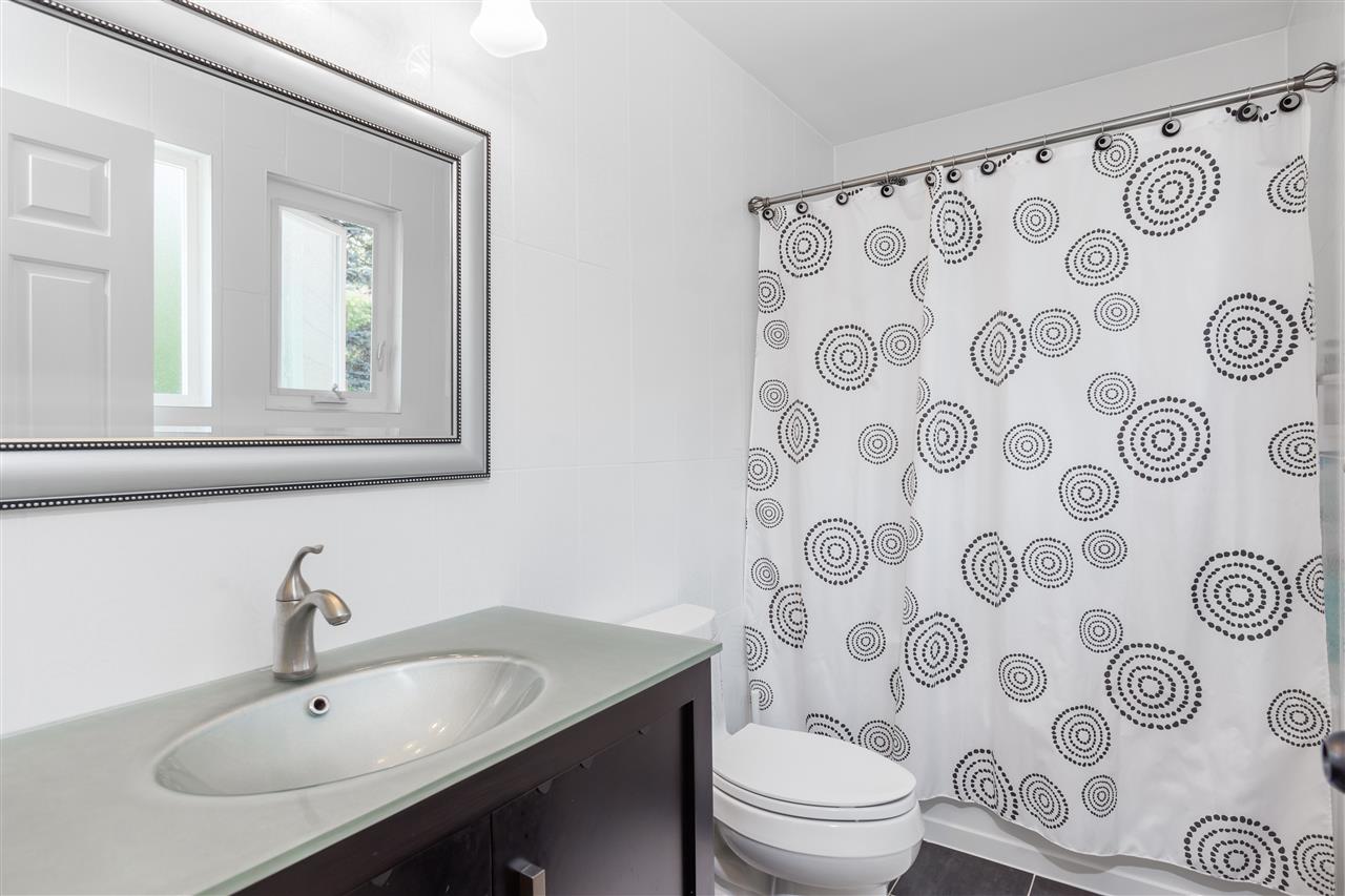 A bathroom below, a green counter vanity with a patterned curtain across the tub.