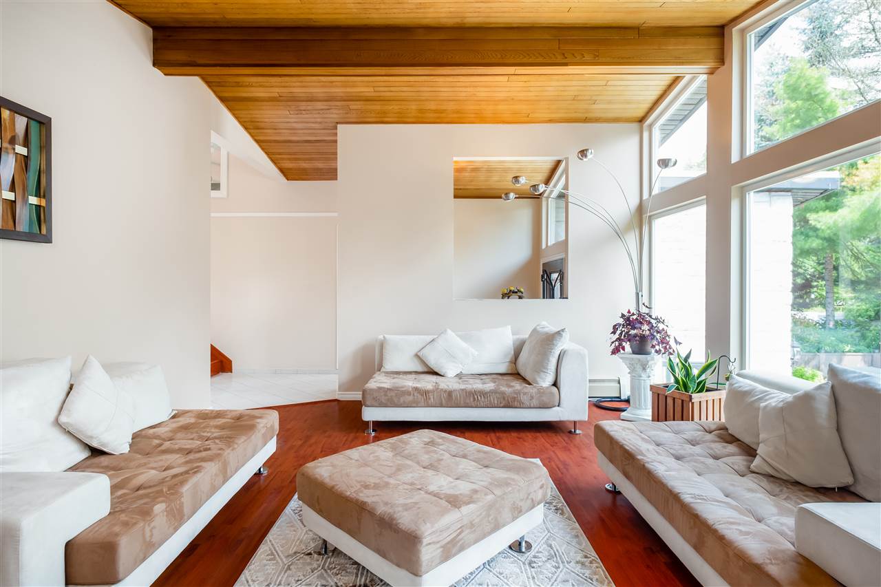 The living room from the far end, the sunken seating and the ottoman with the window wall behind.