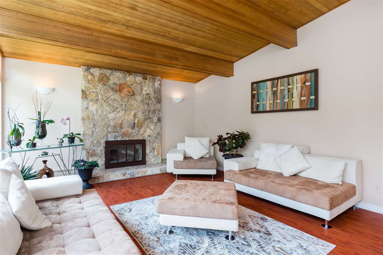 The living room toward the stone fireplace, the cedar ceiling running the length of the room above.