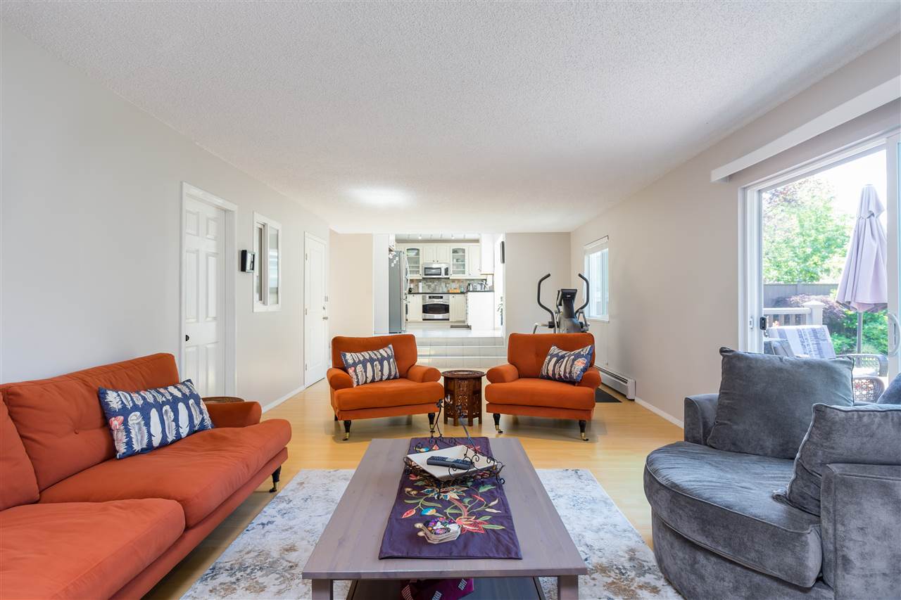 The family room, orange armchairs around a low table with the kitchen pass-through behind.