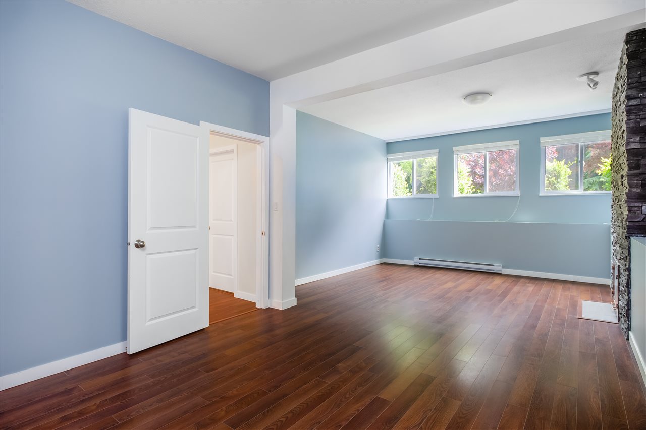 The lower living room, empty, hardwood underfoot and a door through to the hall.