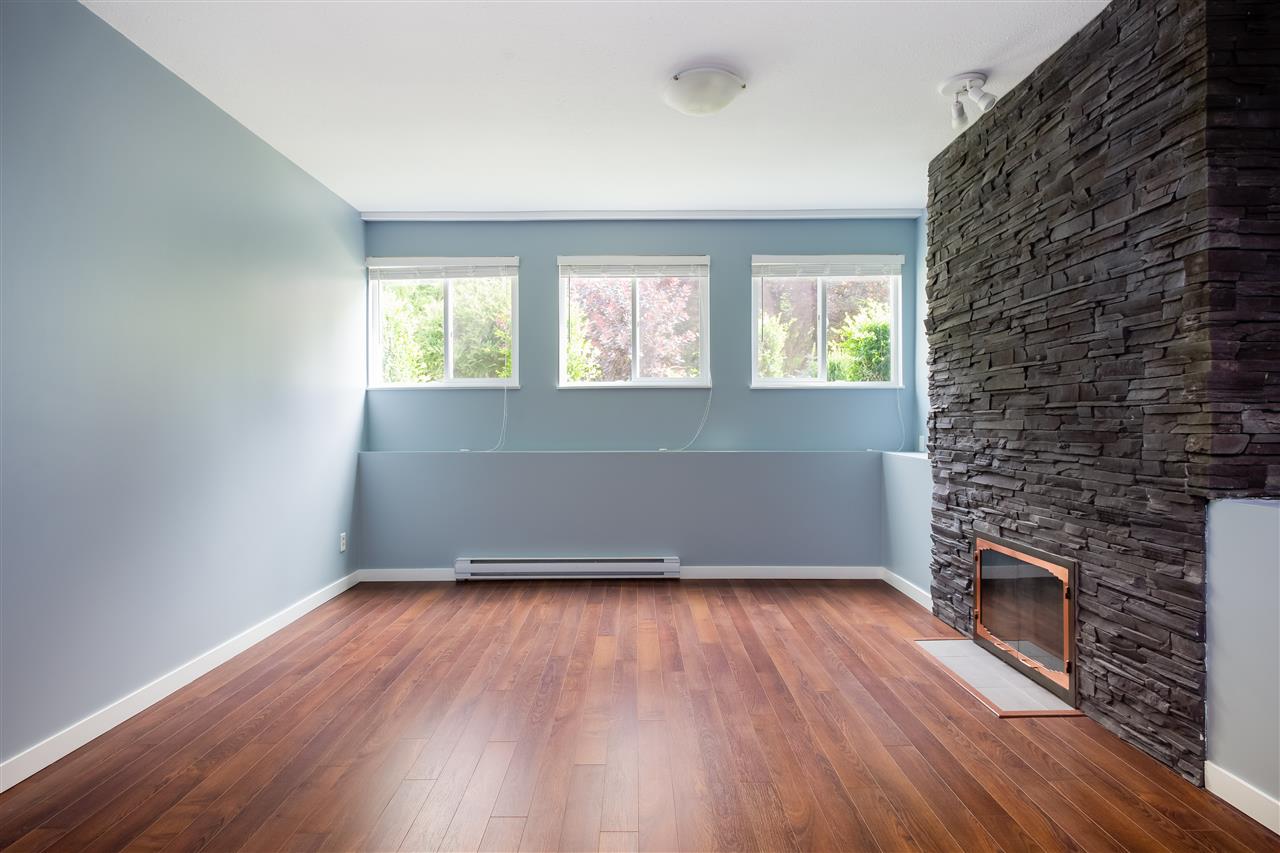 The lower living room toward the stone feature wall, high windows running along the top of the far side.