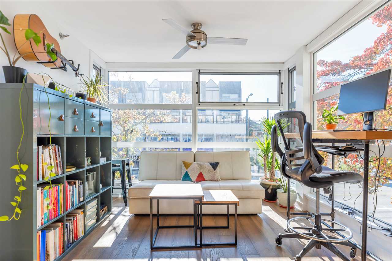 The corner bay off the living room, windows on two sides with a desk and bookshelves.