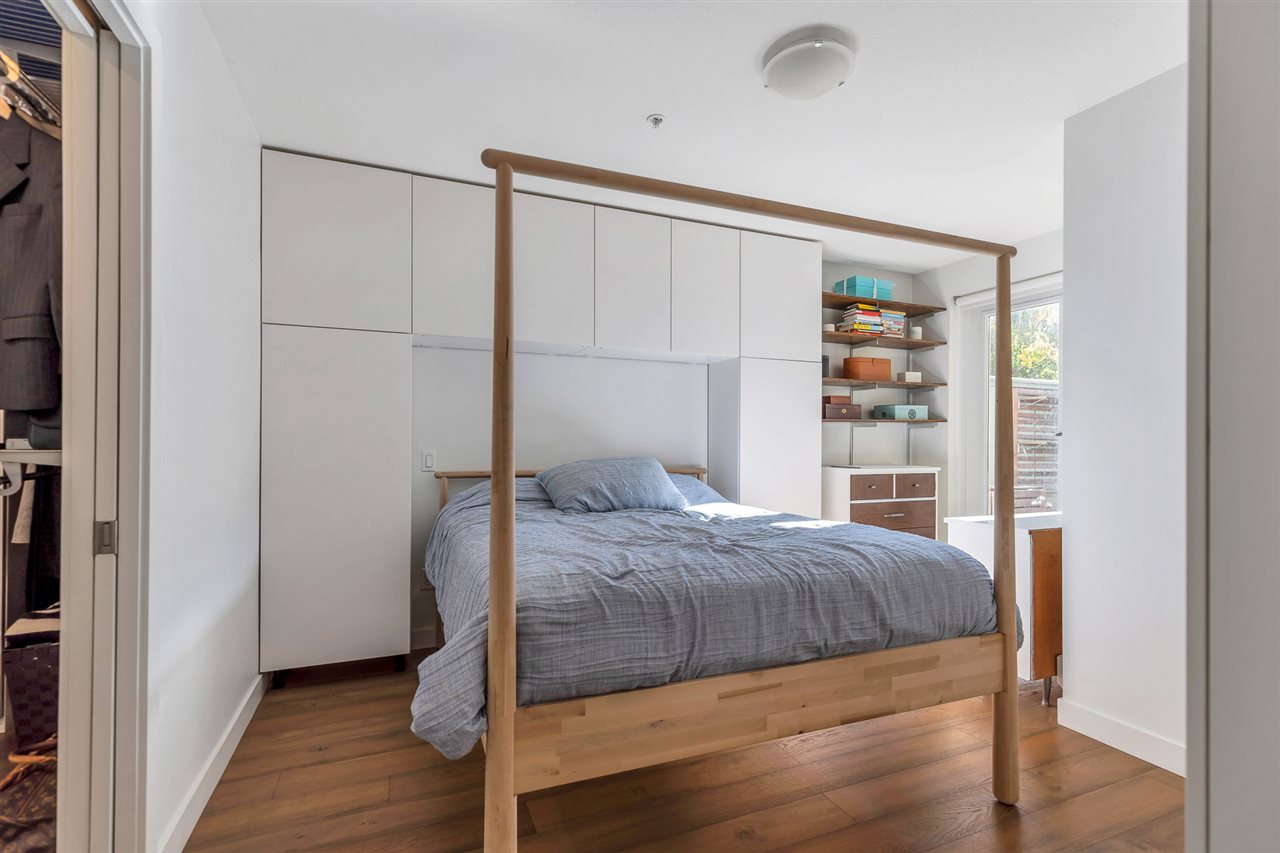 The primary bedroom, a wooden bed frame under fitted cabinetry.