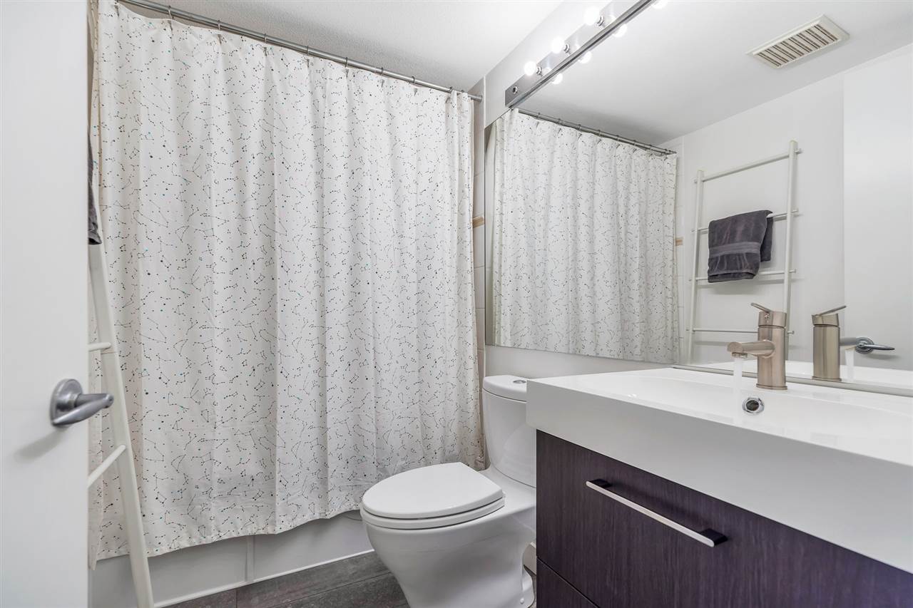 The second bathroom, a vanity and mirror beside the tub.