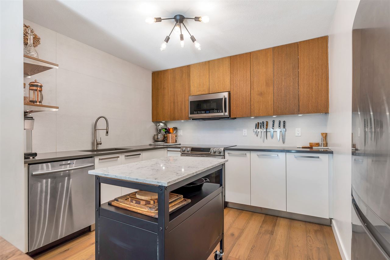 The kitchen, wood uppers over white cabinets with a stone-topped island in the middle.