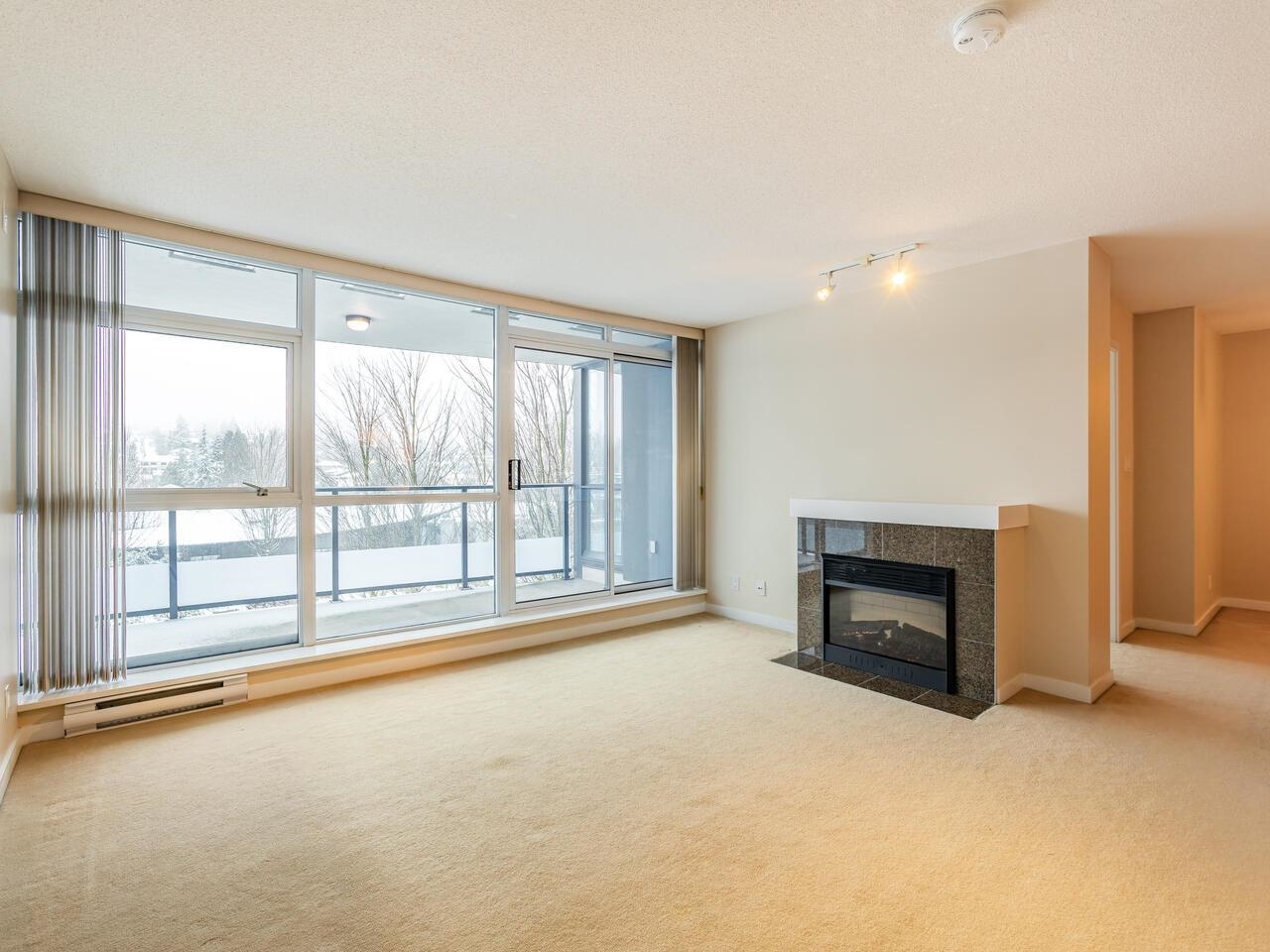 The living room, windows along one wall to the balcony and a fireplace set into the wall beside them.
