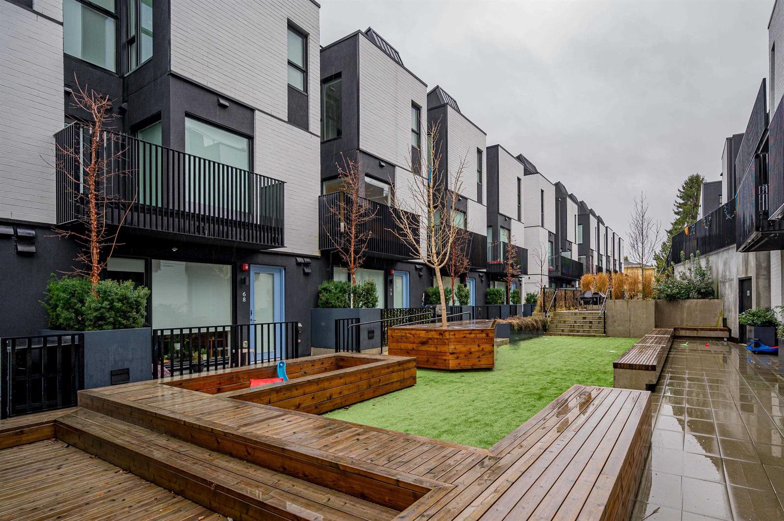 The shared mews between the terraces — timber decking, a strip of lawn and planted beds.