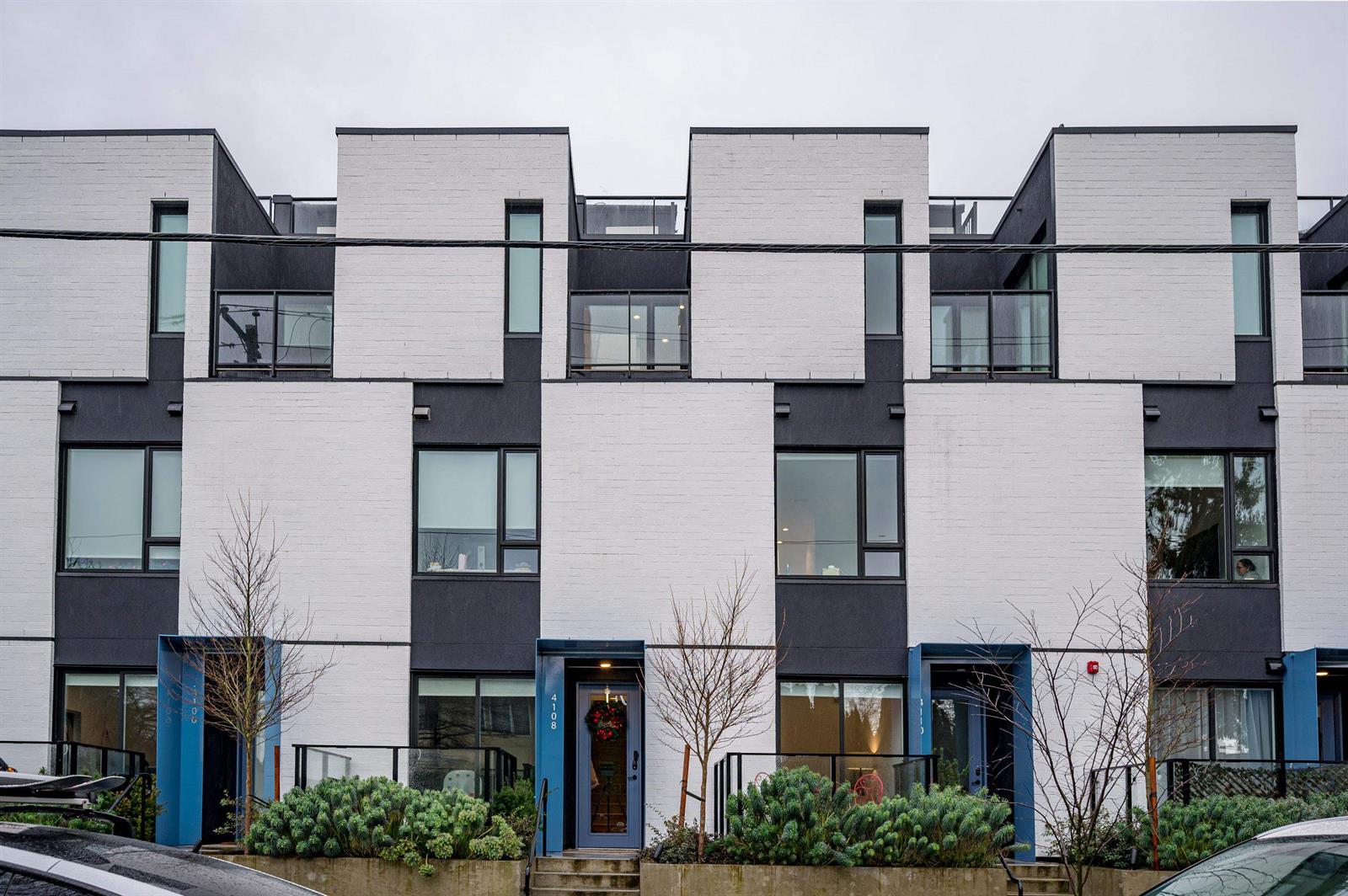 The terrace from the street — white brick below, black upper storeys, each house with its own steps and planting.