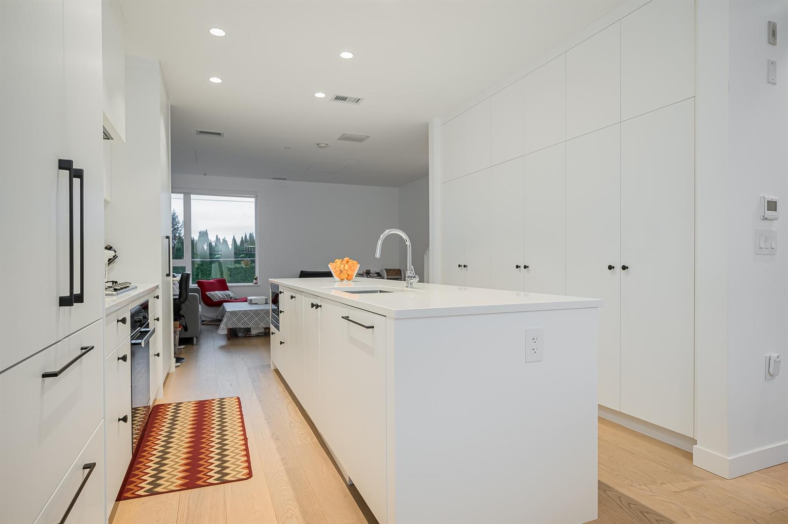 The kitchen from the far end, the island and the run of cupboards leading back towards the window.