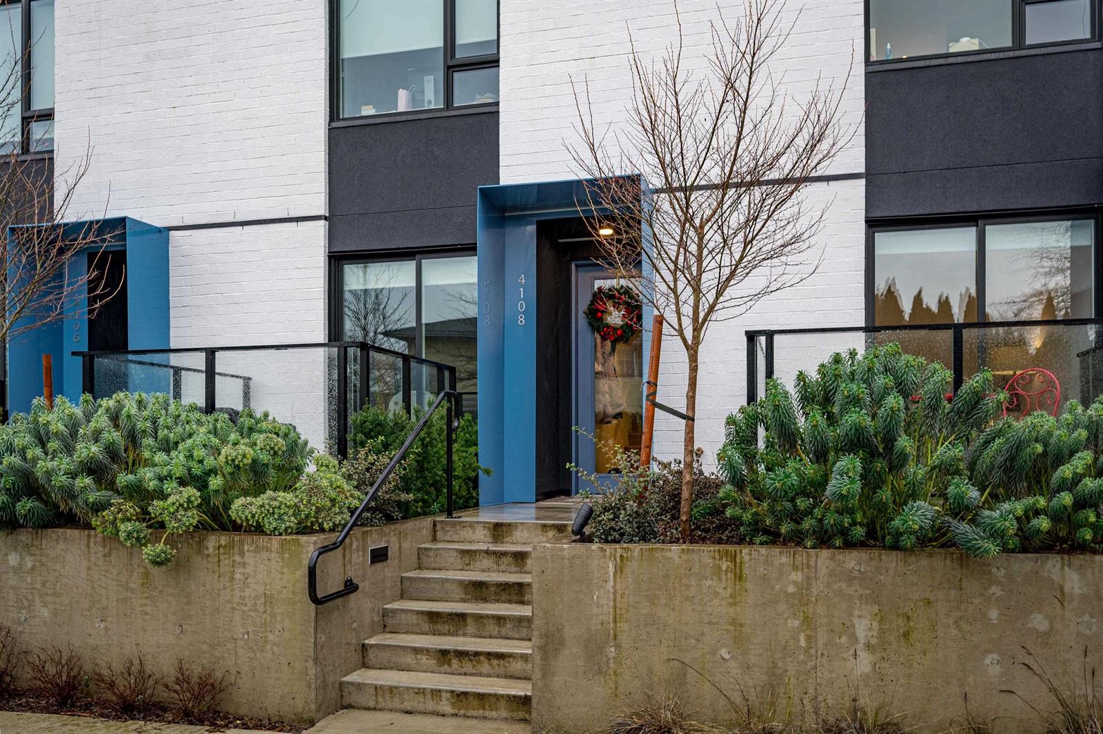 The entrance, up a few steps between planted beds to a blue front door.