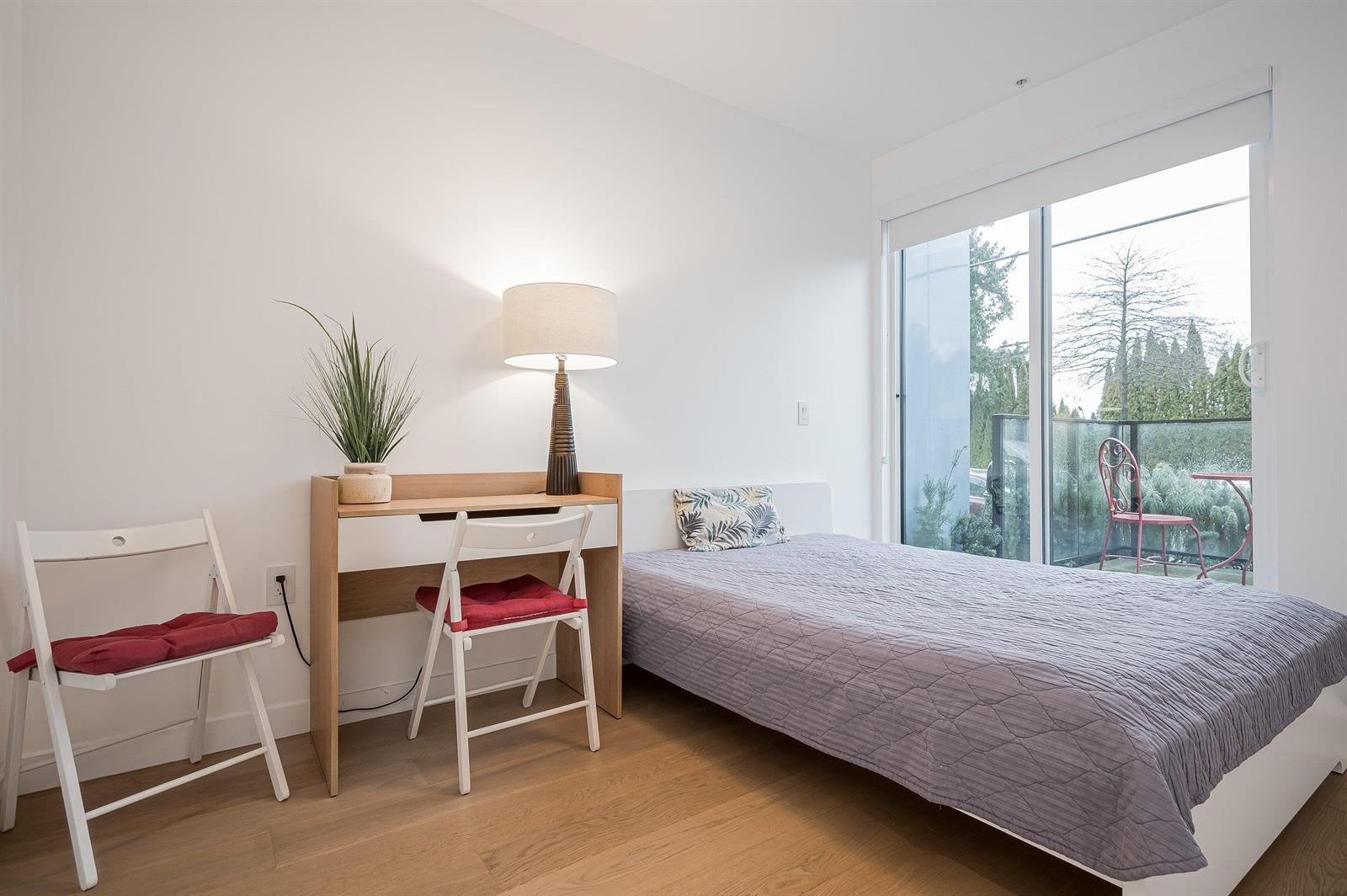 A bedroom with a desk and two chairs set under the window.